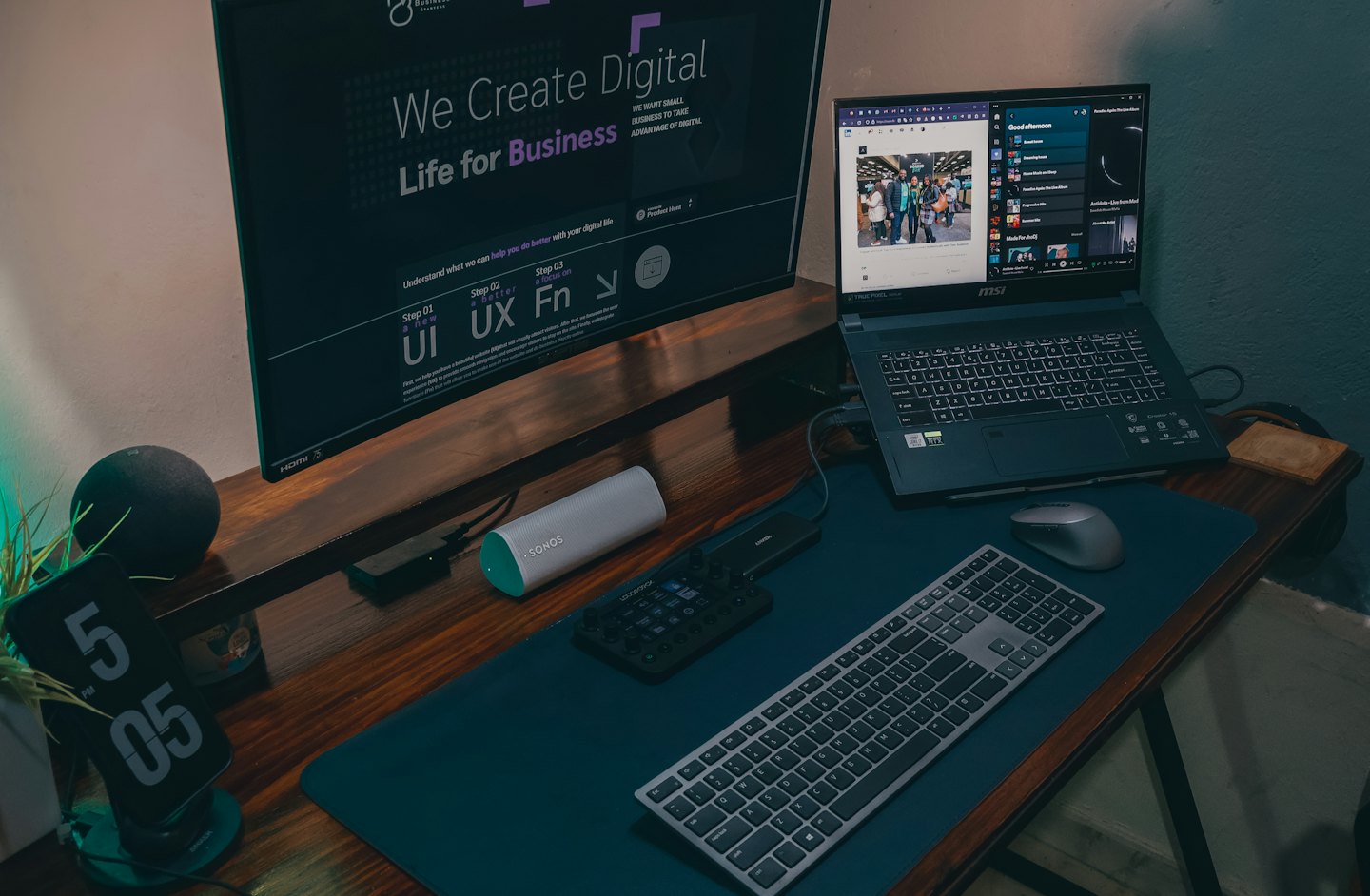 Laptop en monitor met digitale content op een houten bureau.
